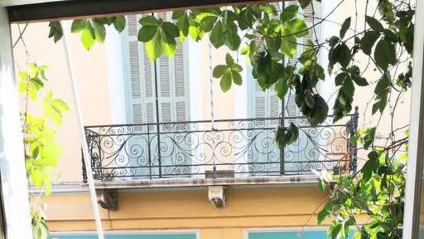 A small outdoor balcony with a round table and two chairs, surrounded by greenery and a decorative metal railing. - Magnificent apartment in Plaka (Athina)