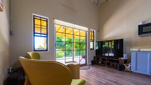 Un salon spacieux doté d’une grande fenêtre, d’un téléviseur à écran plat et d’un plancher en bois.