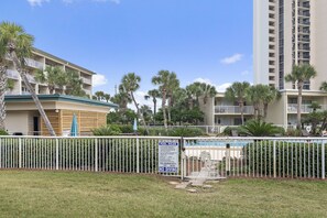 A hotel with a pool area, palm trees, and a sign indicating pool rules. - Beach-side, beautiful low-rise with uncrowded beach! (Destin)