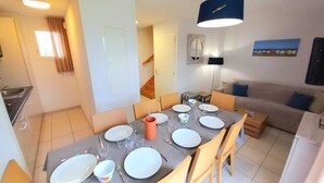 Un coin repas avec une table dressée pour quatre personnes, un canapé, une lampe et un tableau accroché au mur.