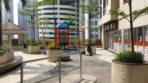A playground with slides and a climbing structure, surrounded by planters and a gazebo.