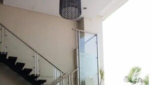 Ein modernes Interieur mit Wendeltreppe aus Glas, einem Ecksofa und Blick auf Grünflächen.