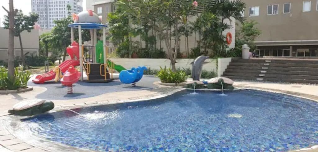 A swimming pool with slides and a dolphin sculpture.