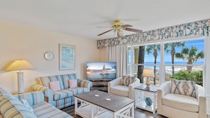A living room with striped sofas, a coffee table, a TV, and a ceiling fan.