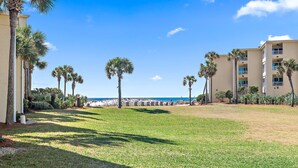 A hotel with a grassy lawn, palm trees, and a view of the beach. - Freshly renovated! Beachfront property! (Destin)