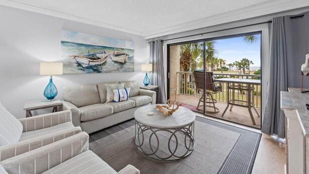 A modern living room with a sofa, coffee table, and a painting of boats on the wall.