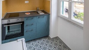 Eine kleine Küche mit Backofen, Spüle und einem Fenster mit Blick auf die Straße.