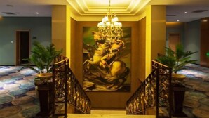 A grand staircase with a chandelier, flanked by potted plants, leading to a room with a large mural. - Xixia Kunpeng Hotel (Xixia)