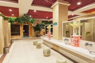 Un vestíbulo de hotel con una recepción, un espejo grande y una planta en maceta.