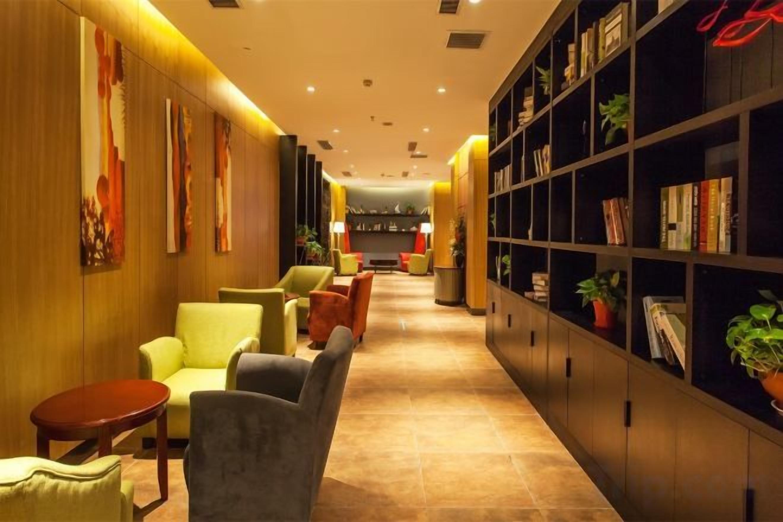 A hotel lobby with seating, a reception desk, and a bookshelf.