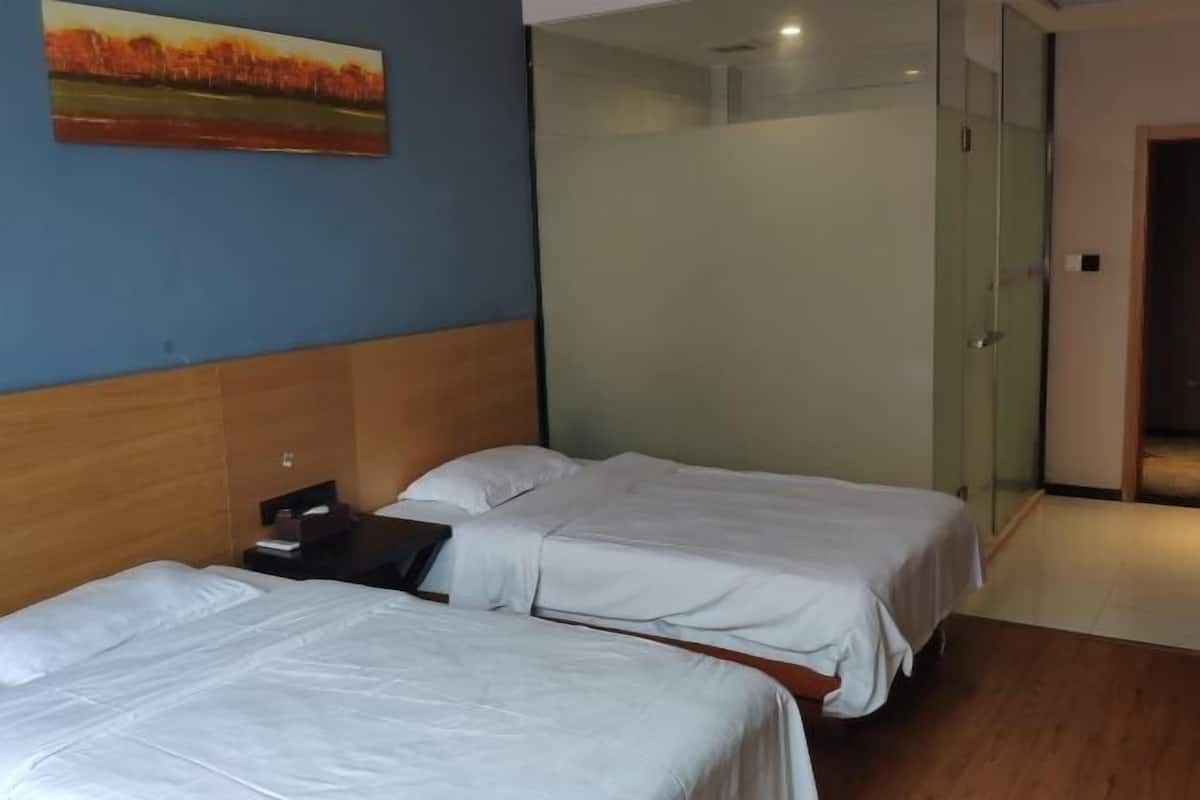 A hotel room with two beds, a wooden headboard, a nightstand, and a painting on the wall.