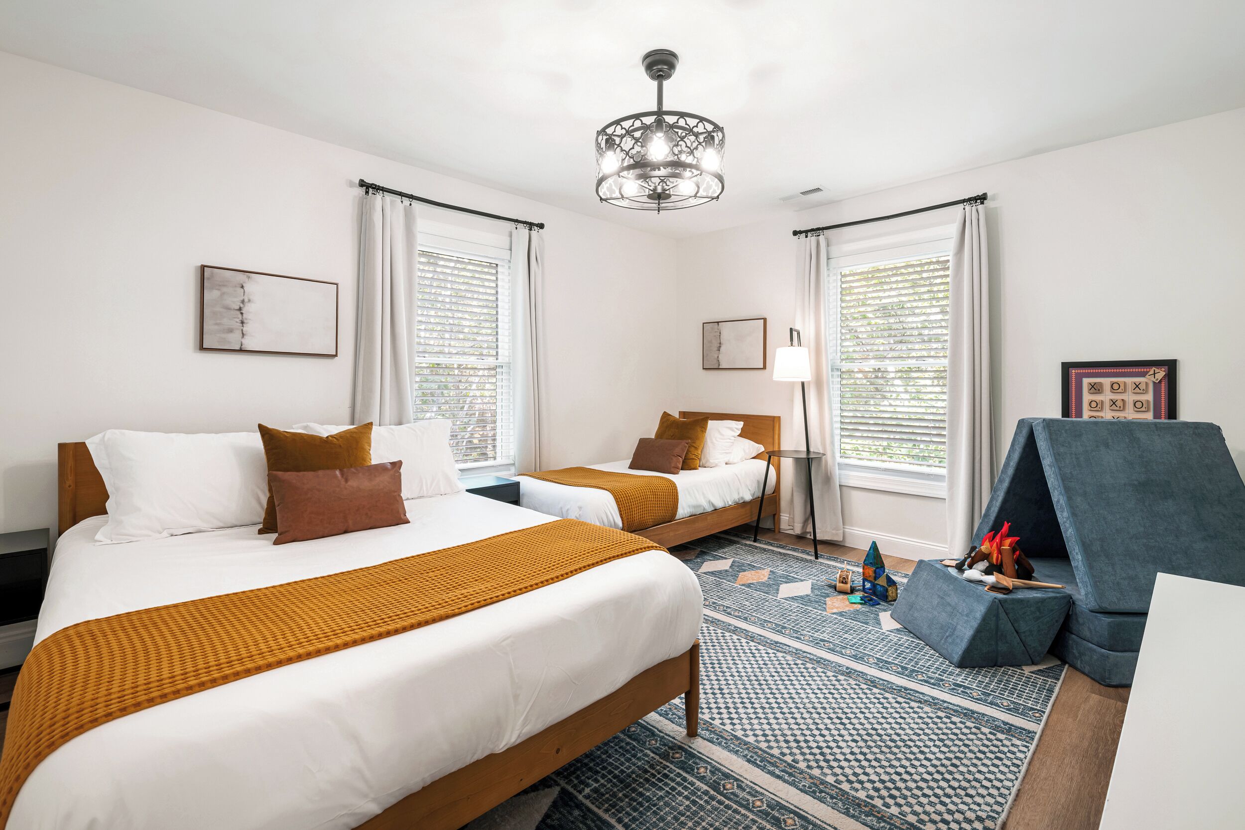 Een hotelkamer met twee bedden, een kroonluchter, een blauwe bank en een kamerbreed tapijt met dessin.