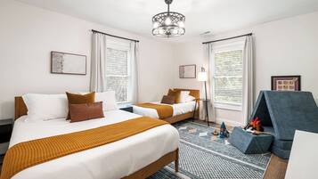 Een hotelkamer met twee bedden, een kroonluchter, een blauwe bank en een kamerbreed tapijt met dessin.