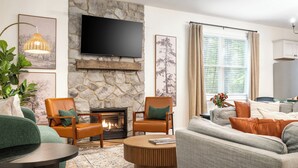 A living room with a stone fireplace, a flat-screen TV, and a large window with curtains. - Top Shenandoah Stay | 4BR w/ 2 King Suites | Private | Easy Drive | Newly Built (McGaheysville)
