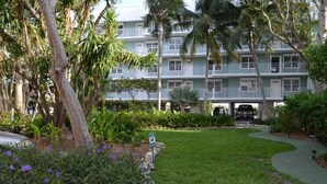 A hotel with a lush garden, palm trees, and a pathway leading to the entrance. - The Crown Jewel of La Brisa 2 bdrm Monthly Spectacular ocean views. (Key West)