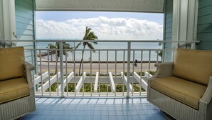 A balcony with wicker furniture, a view of the beach, and a palm tree. - The Crown Jewel of La Brisa 2 bdrm Monthly Spectacular ocean views. (Key West)