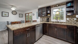 A modern kitchen with dark wood cabinets, granite countertops, and a built-in dishwasher. - Close to Lewes with community pool, tennis & a fishing pier! 23290 Bridgeway (Lewes)