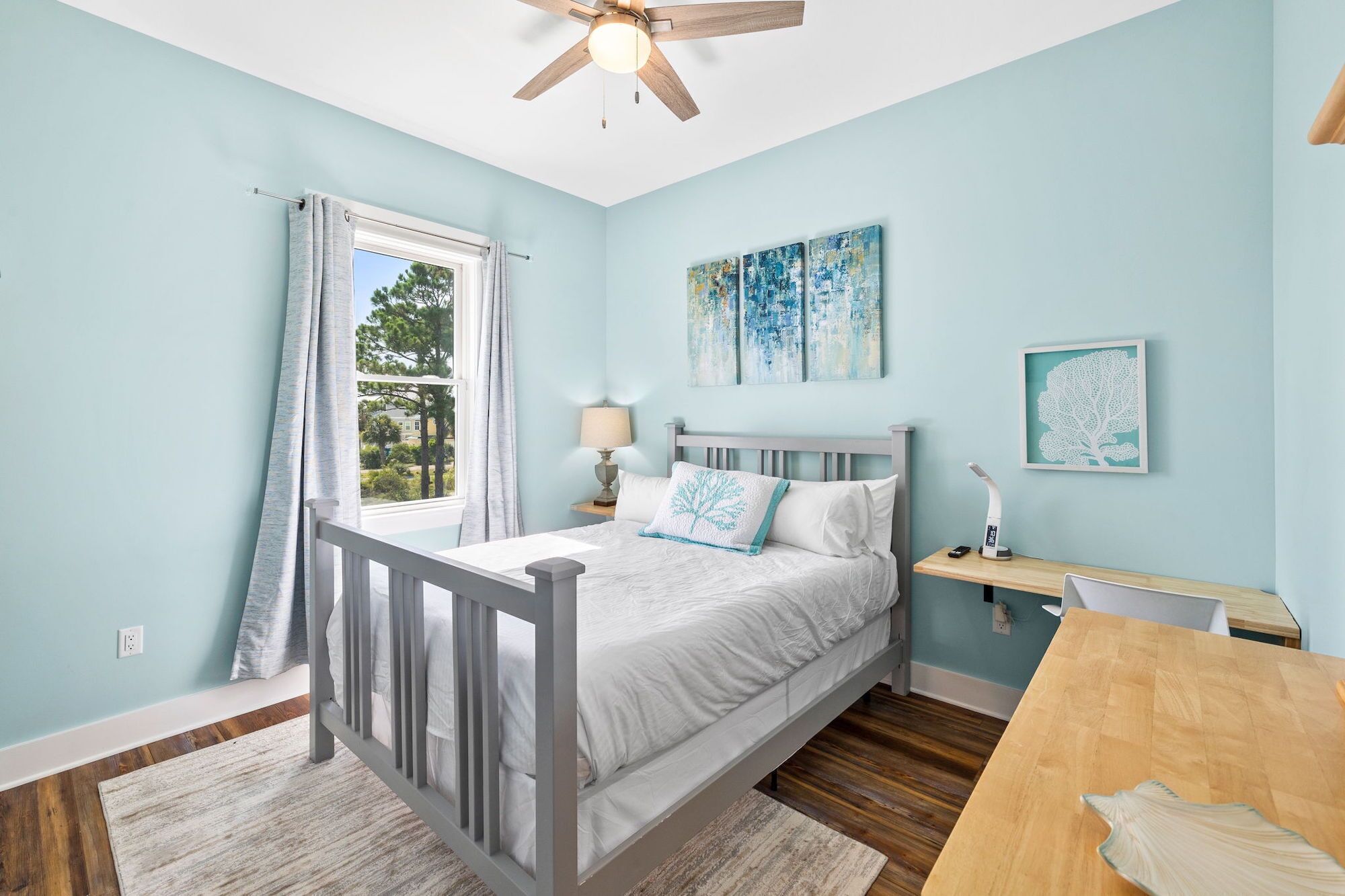 A bedroom with a bed, a nightstand, a desk, and a ceiling fan.