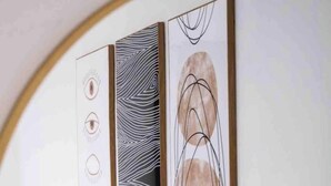 Ein Schlafzimmer mit einem weißen Kopfteil, einem Bett mit zwei Kissen und einem Wandbild darüber.