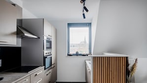A modern kitchen with a built-in oven, a stove, and a window with a view of a building.