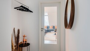 A modern entryway with a white door, a round mirror, and a black coat rack.