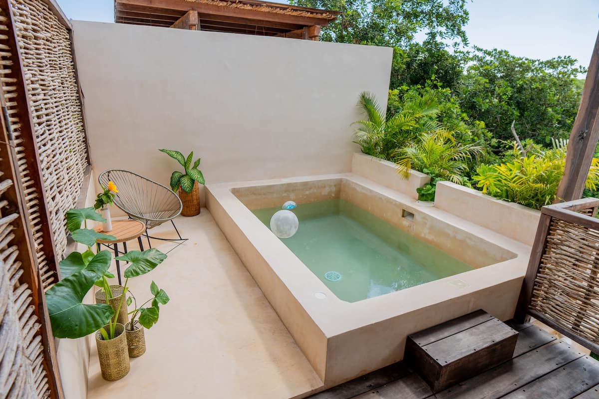 A spa area with a hot tub, wicker furniture, and potted plants.