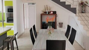 Een moderne keuken met een eethoek, een trap en een klok aan de muur.