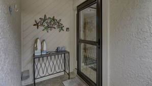 A white textured wall with a metal console table displaying decorative items and a sign reading "Welcome to the Beach." - Sunset Rentals | Continental Club 6 (HIlton Head Island)