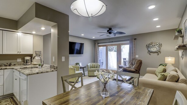 A modern kitchen with white cabinets, a dining table, and a ceiling fan. - Sunset Rentals | Continental Club 6 (HIlton Head Island)