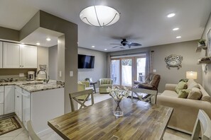 A modern kitchen with white cabinets, a dining table, and a ceiling fan.