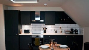 A modern kitchen with dark cabinets, white subway tiles, and a dining area with a round table and chairs.