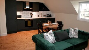 Een moderne keuken met donkere kastjes, een witte werkblad en een eethoek met een houten tafel en stoelen.