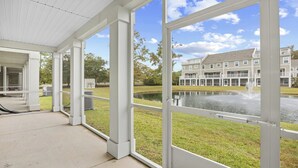 A covered outdoor area with large windows overlooking a building and a pond. - Newly built, open-concept, and beautifully decorated 4 Bedroom in Barefoot Resort!<br>802 Dye Townhome (North Myrtle Beach)
