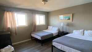 A hotel room with two single beds, a desk, a chair, and a window with curtains. - Lakeshore-Bachelor/Bachelorette Parties welcomed! (Lake Ozark)
