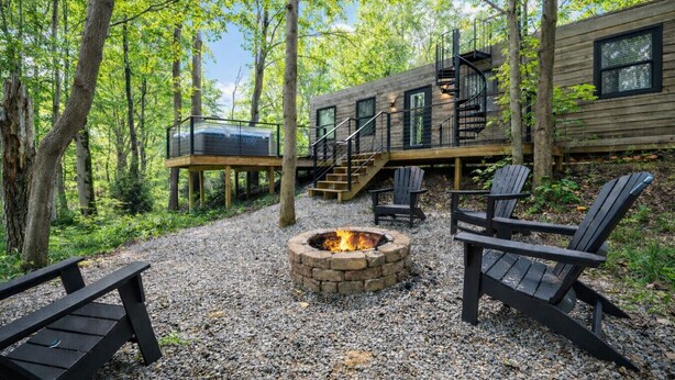 Uma cabana com lareira, área de estar externa e um deck.