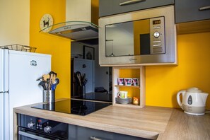 A modern kitchen with a microwave, stove, and kettle. - L'Abstrait - T3 avec parking à 5 minutes du port (Vannes)