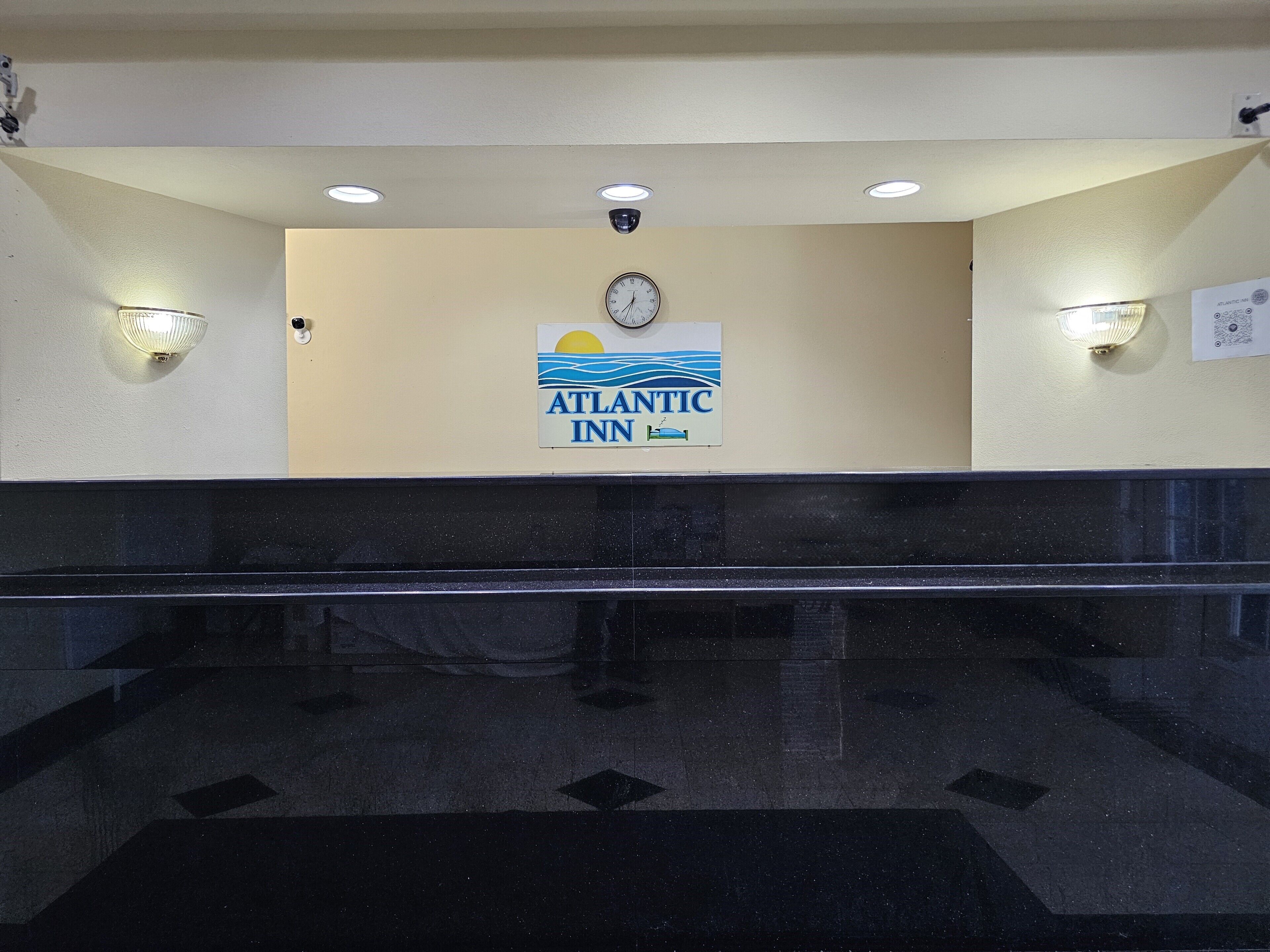 A lobby with a clock, a sign for Atlantic Inn, and two wall-mounted lights.