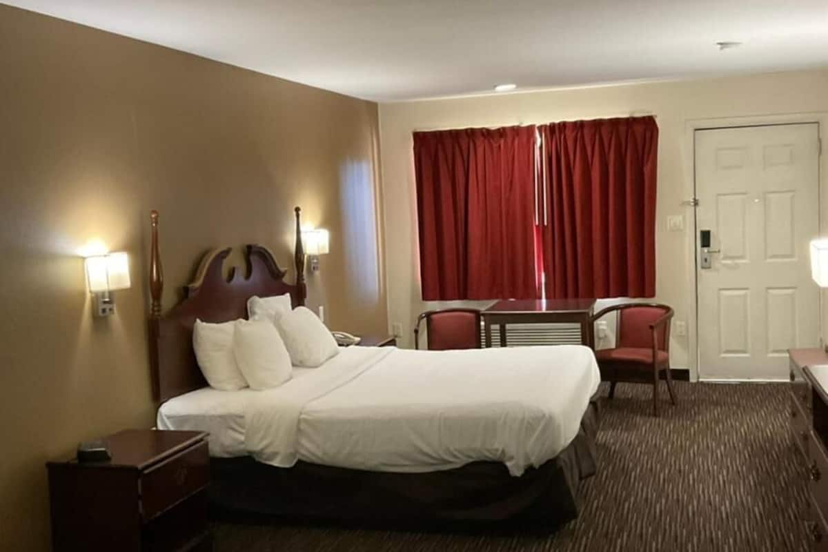 A hotel room with a bed, bedside tables, a desk, and a chair.
