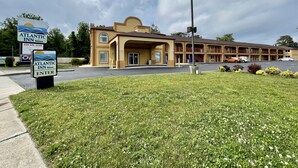 A motel with a large parking lot, a covered entrance, and a sign indicating the Atlantic Inn. - ATLANTIC INN (Pleasantville)