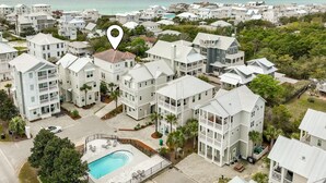 A residential area with multiple two-story houses, a swimming pool, and a view of the ocean.