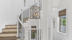 A staircase with white railings and a geometric hanging light fixture.