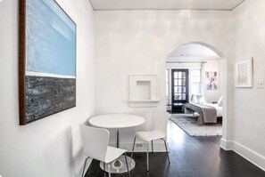 A modern interior with a round table and two chairs, a large abstract painting, and a doorway leading to another room. - Historic Candler Park Gem! -Sleeps 4- Apt 3 - AC Atlanta (Atlanta)