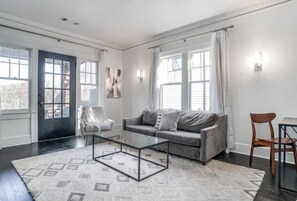 A living room with a grey sofa, a glass coffee table, a patterned rug, and a chair.