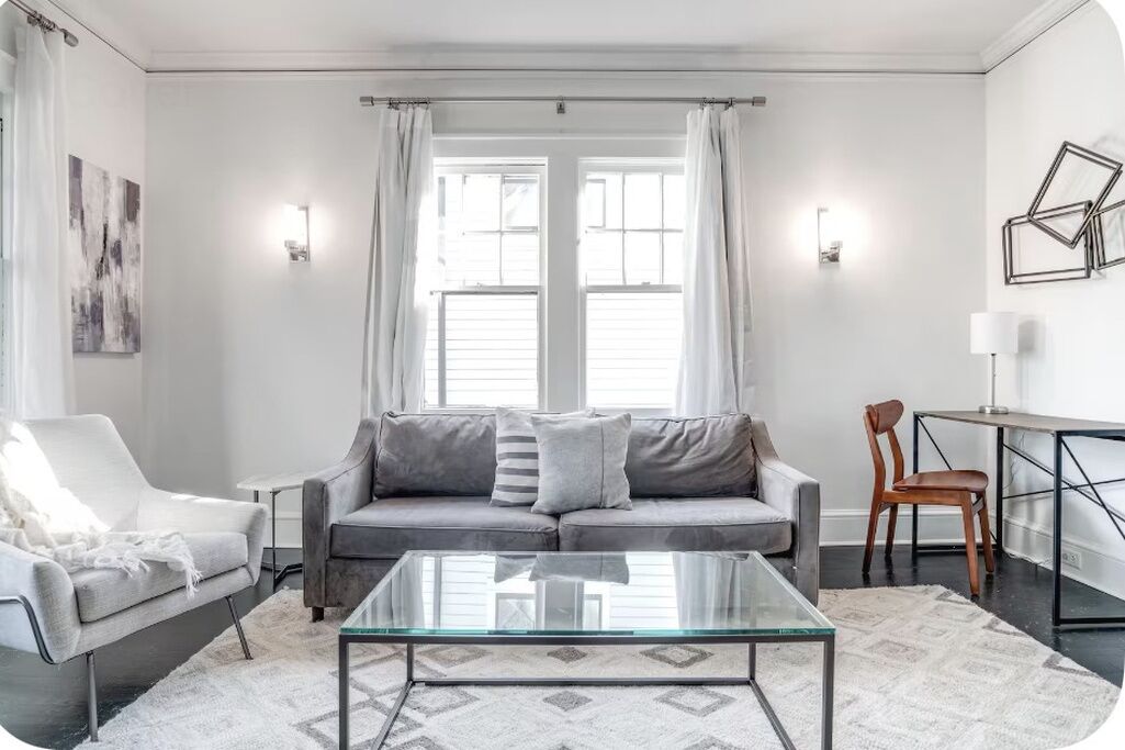 A modern living room with a sofa, a glass coffee table, and a chair.