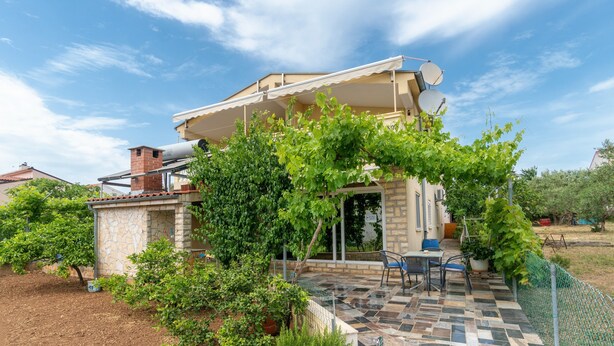 Una casa con patio, muros de piedra y jardín.