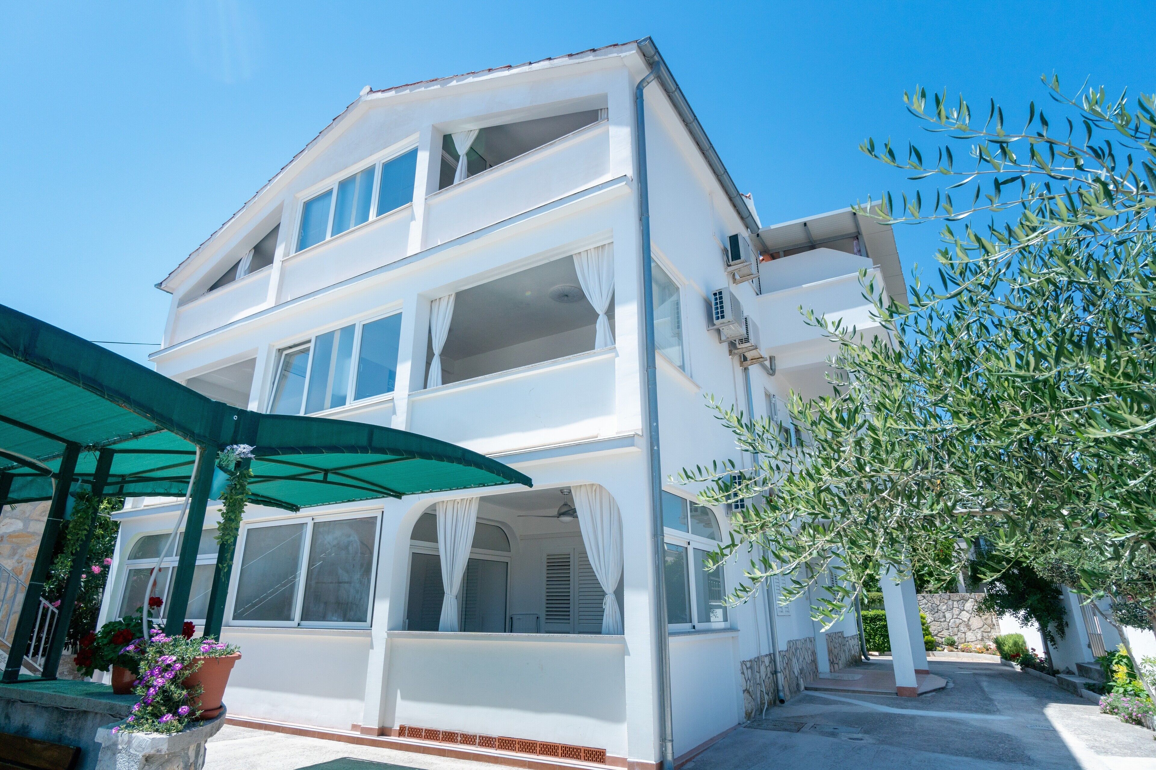 A two-story building with a balcony, a covered outdoor seating area, and a stone wall.