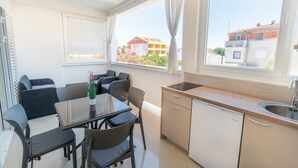 A compact kitchen with a sink, a dining table with chairs, and a window with curtains.