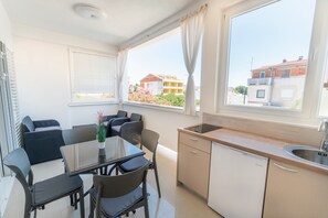 Une cuisine de taille réduite, équipée d’un évier, d’une table à manger avec des chaises et d’une fenêtre avec des rideaux.