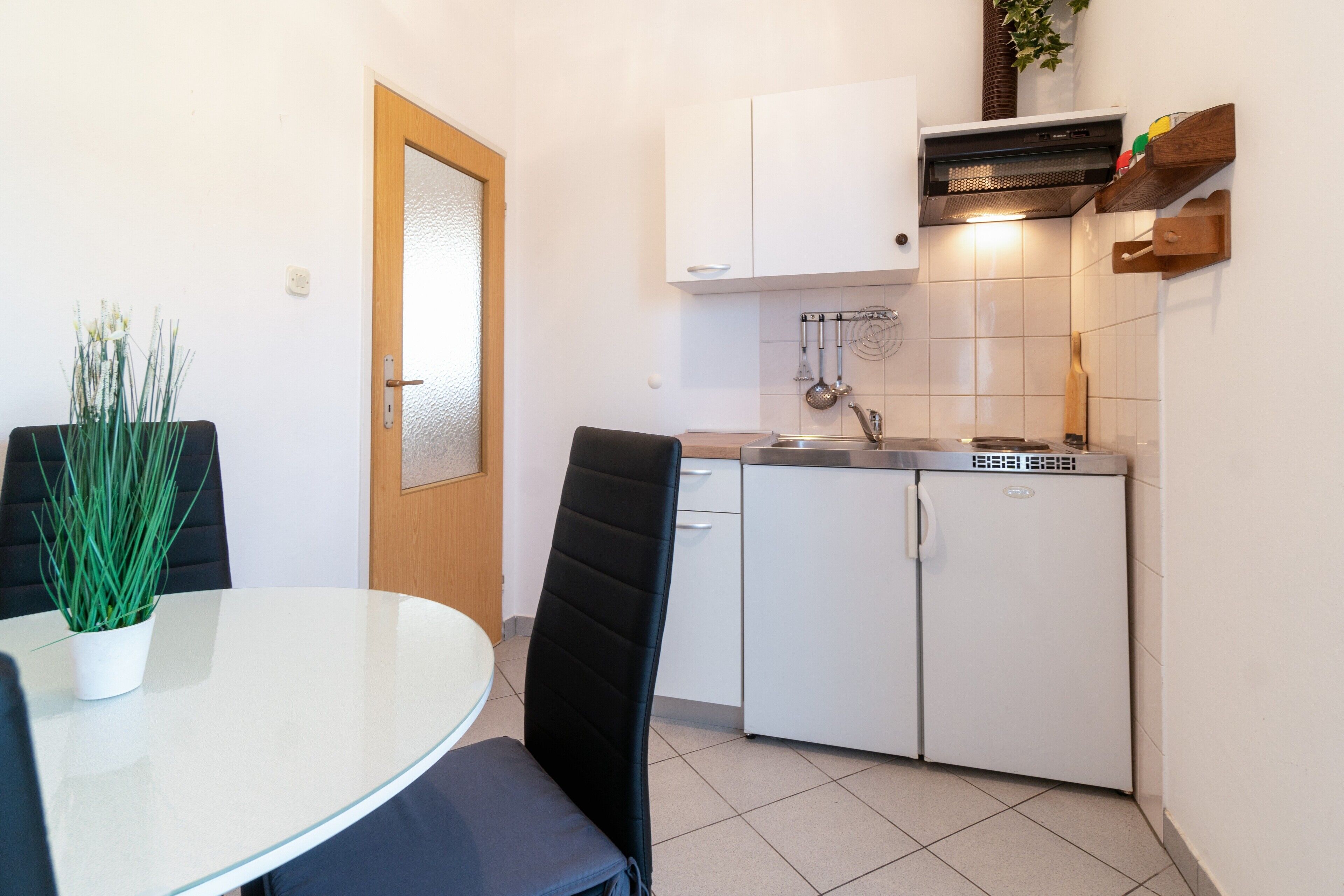 A compact kitchen with white cabinets, a built-in stove, and a small refrigerator.