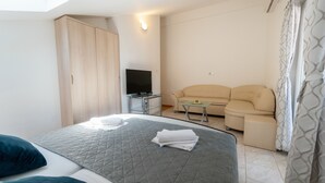 Een hotelkamer met een bed, een bank, een televisie en een bijzettafeltje.